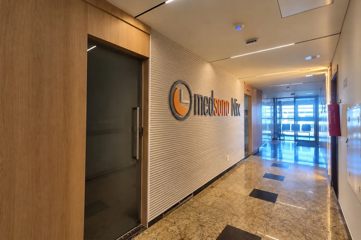 Entrada da unidade, com o letreiro MedSono Nix na parede de ripas brancas